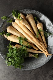 Photo of Parsley roots with leaves on black table, top view