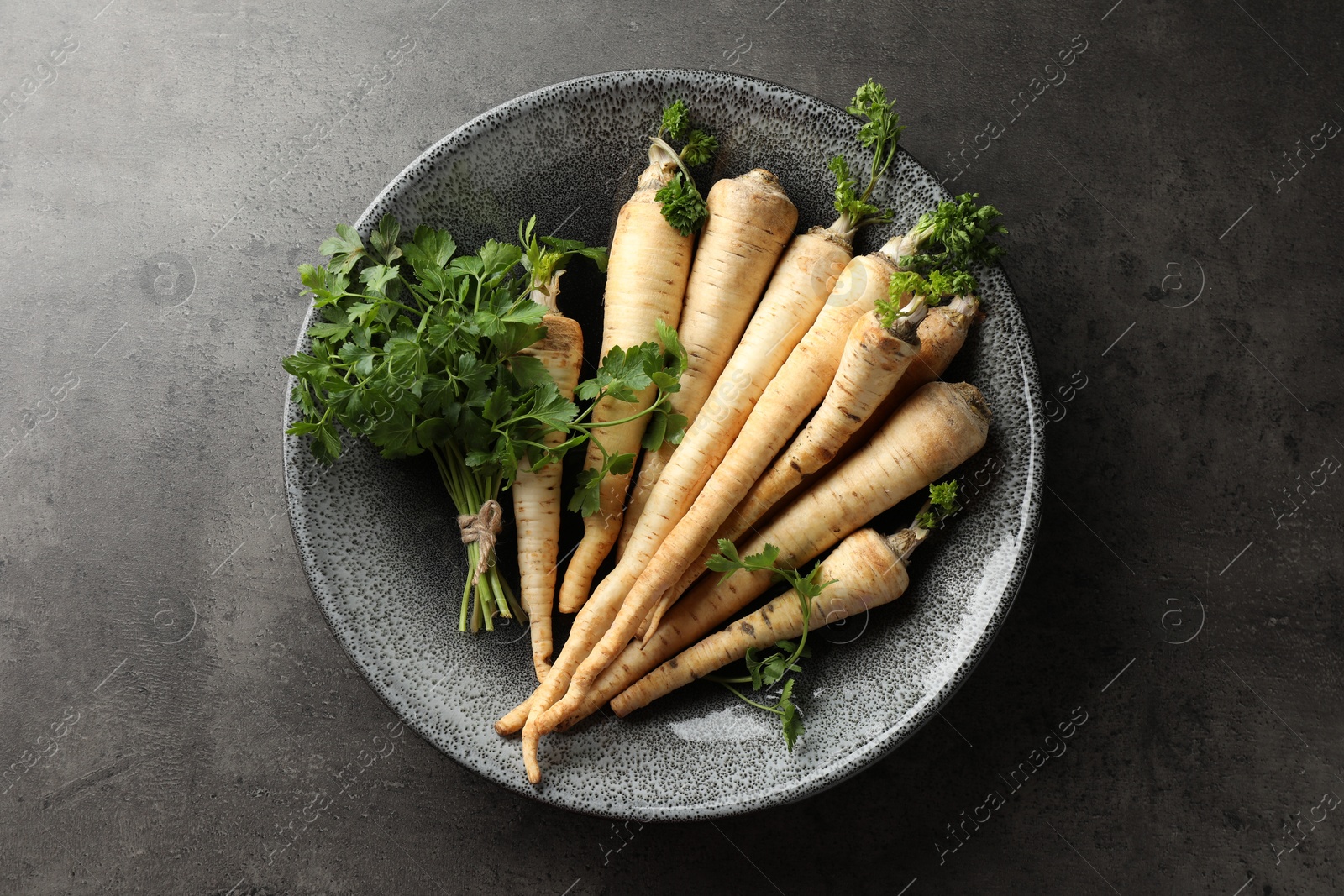 Photo of Parsley roots with leaves on black table, top view