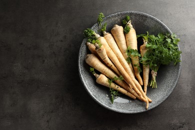 Photo of Parsley roots with leaves on black table, top view. Space for text