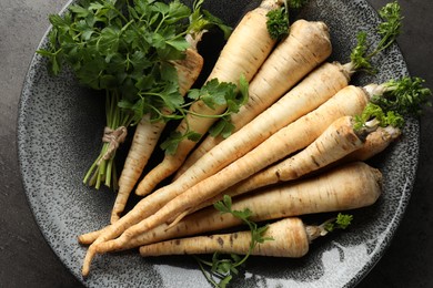 Photo of Parsley roots with leaves on black table, top view