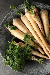 Photo of Parsley roots with leaves on black table, top view