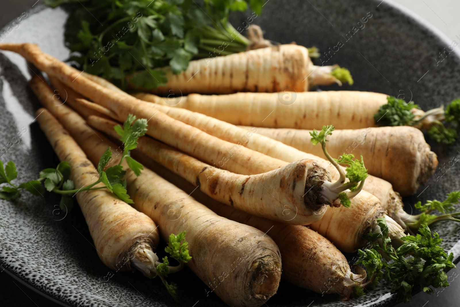 Photo of Parsley roots with leaves on table, closeup