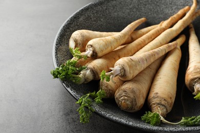 Photo of Parsley roots with leaves on black table, closeup