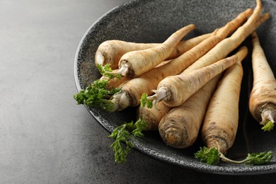 Photo of Parsley roots with leaves on black table, closeup