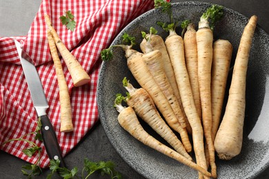 Photo of Parsley roots with leaves and knife on black table, flat lay