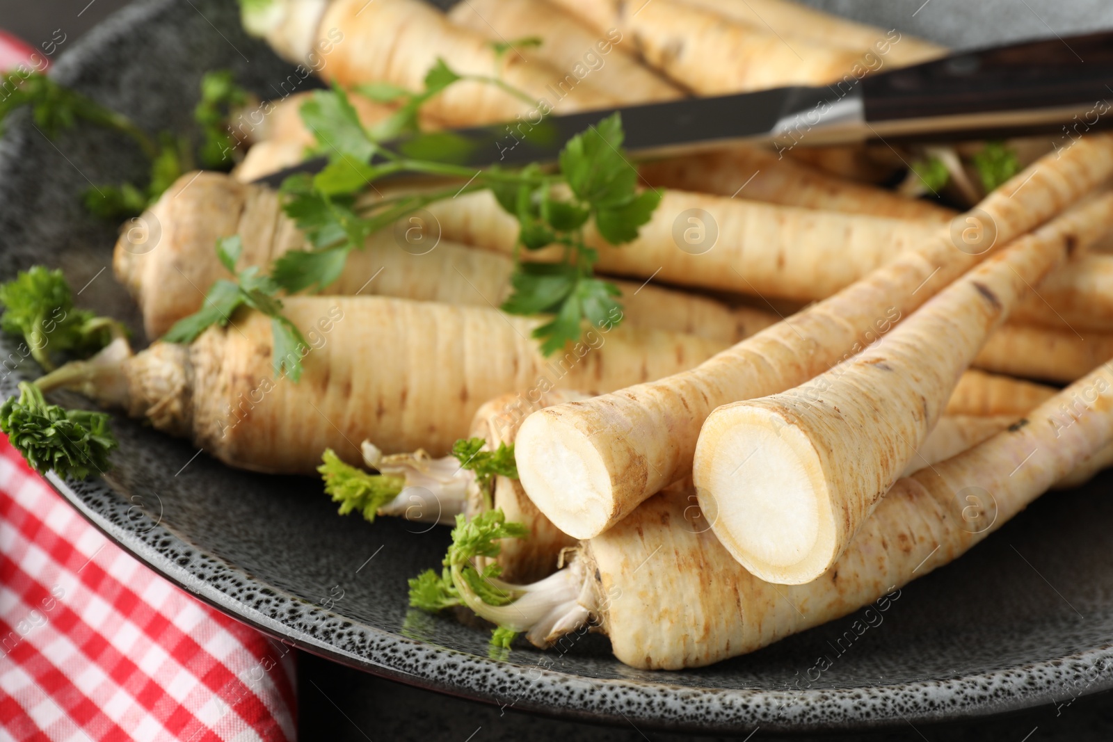 Photo of Parsley roots with leaves and knife on table, closeup