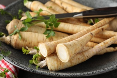 Photo of Parsley roots with leaves and knife on table, closeup