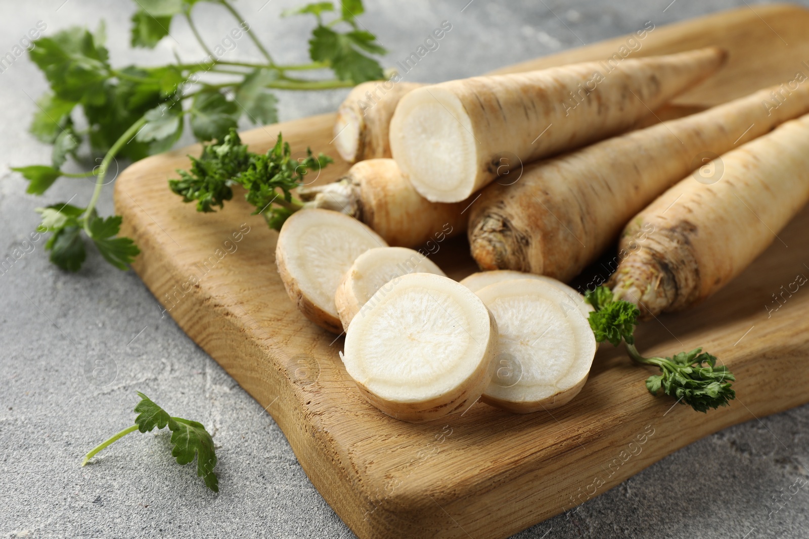 Photo of Parsley roots and leaves on grey table, closeup