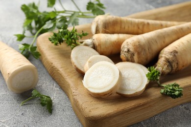 Photo of Parsley roots and leaves on grey table, closeup