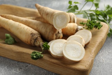 Photo of Parsley roots and leaves on grey table, closeup