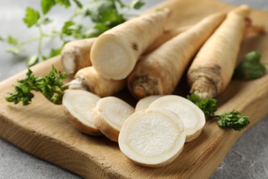 Photo of Parsley roots and leaves on grey table, closeup