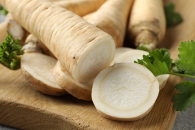 Photo of Parsley roots and leaves on grey table, closeup