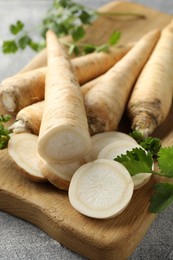 Photo of Parsley roots and leaves on grey table, closeup