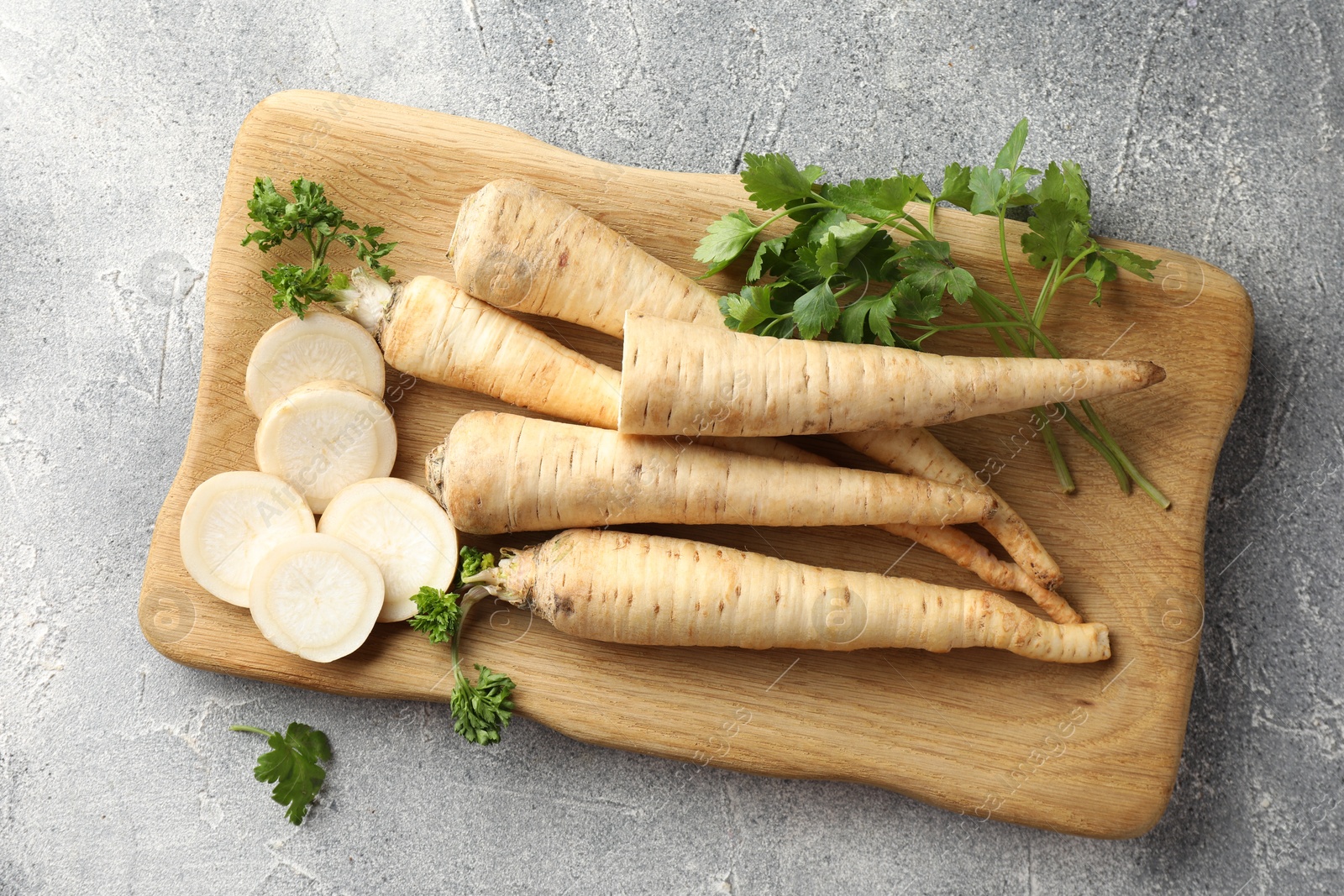 Photo of Parsley roots and leaves on grey table, top view