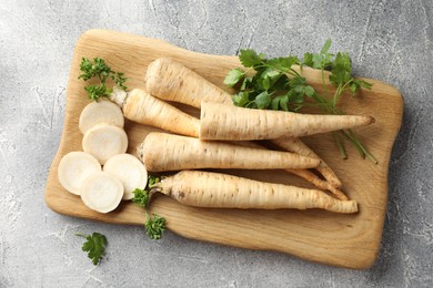 Photo of Parsley roots and leaves on grey table, top view