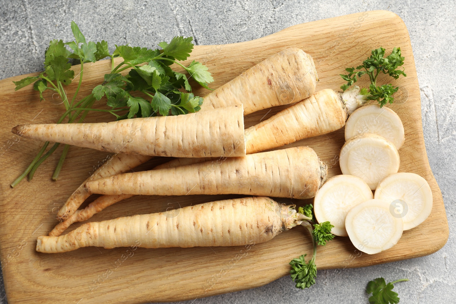 Photo of Parsley roots and leaves on grey table, top view