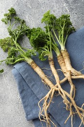 Photo of Parsley roots with leaves on grey table, top view