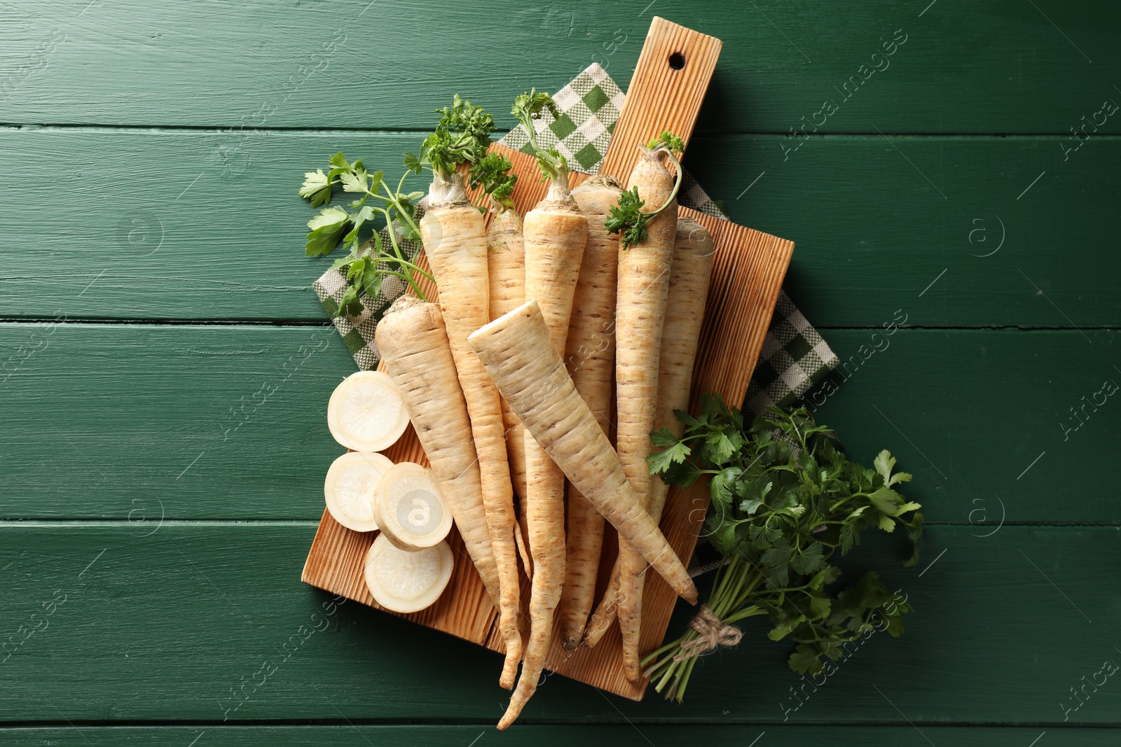 Photo of Parsley roots and leaves on green wooden table, top view