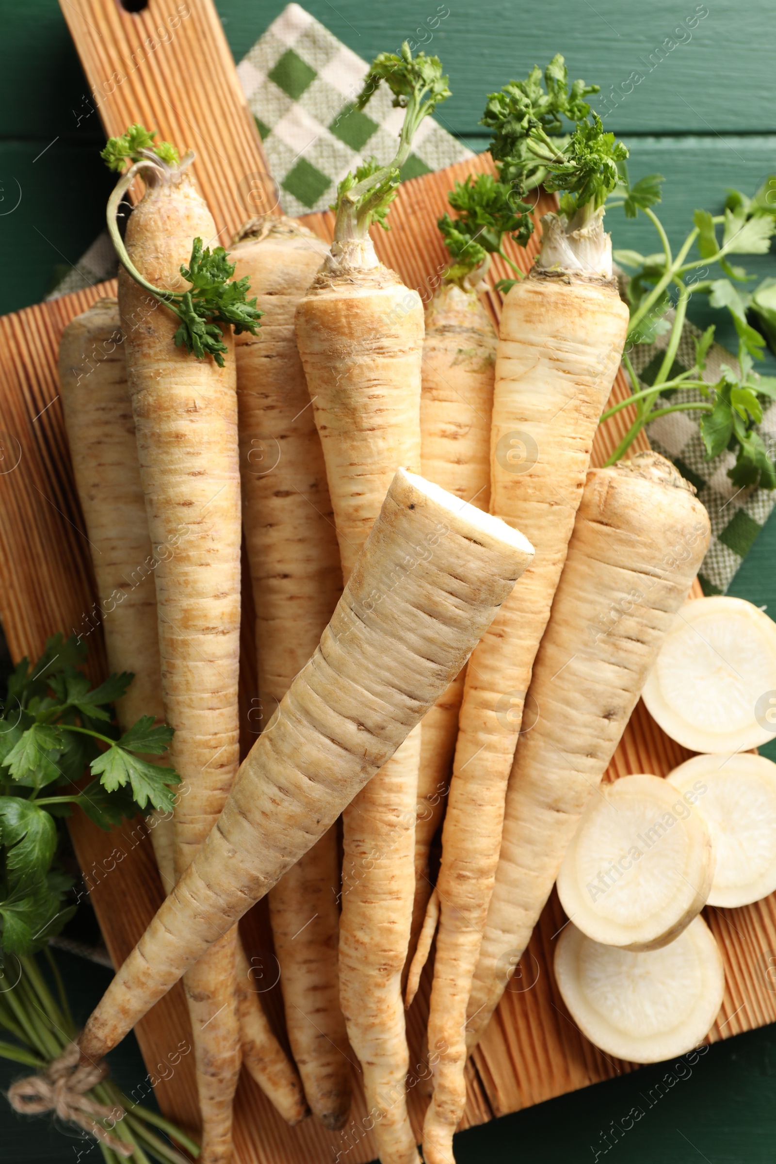 Photo of Parsley roots and leaves on green wooden table, top view