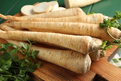 Photo of Parsley roots with leaves on green wooden table, closeup