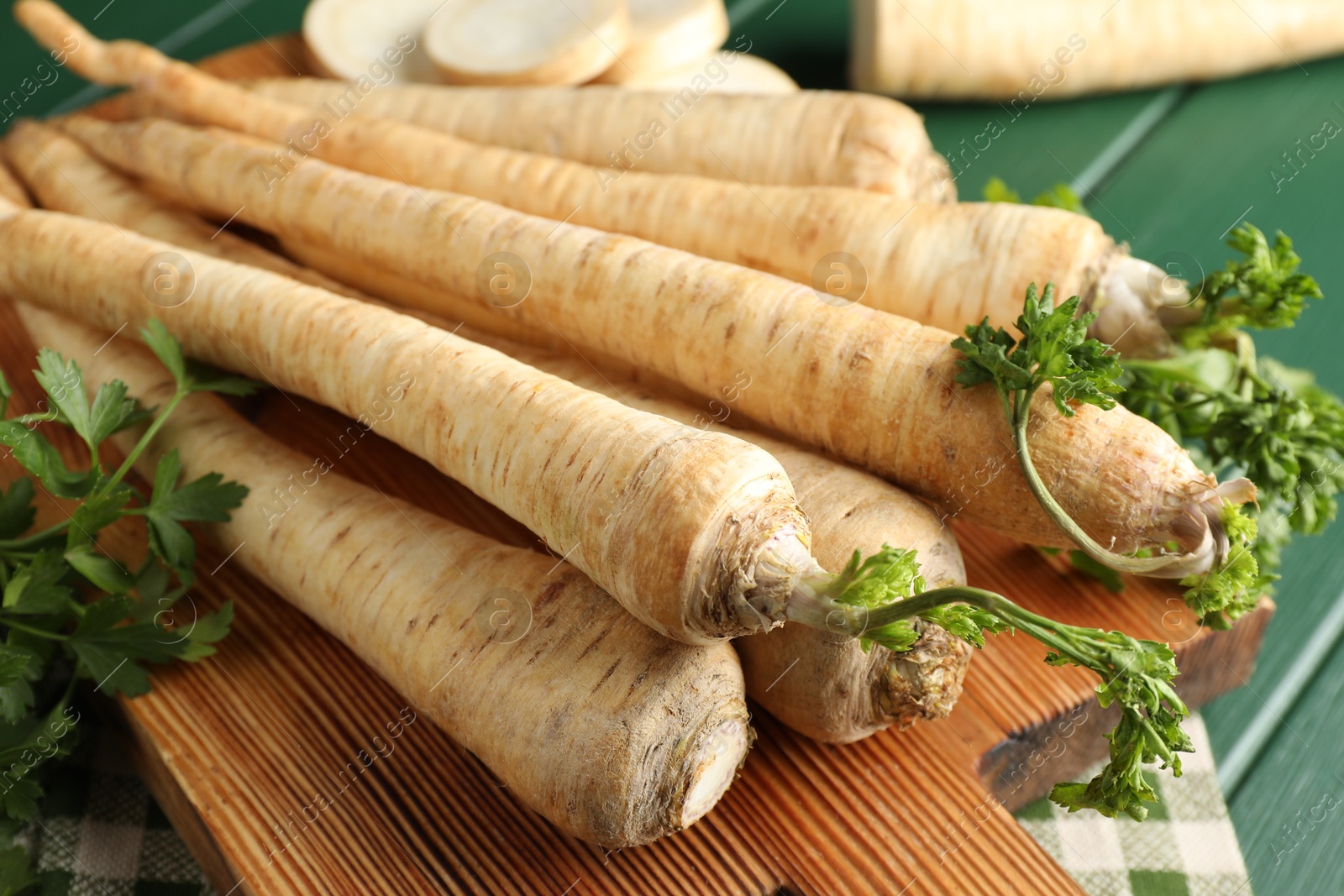 Photo of Parsley roots with leaves on green wooden table, closeup