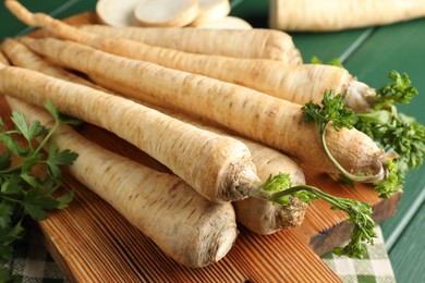 Photo of Parsley roots with leaves on green wooden table, closeup