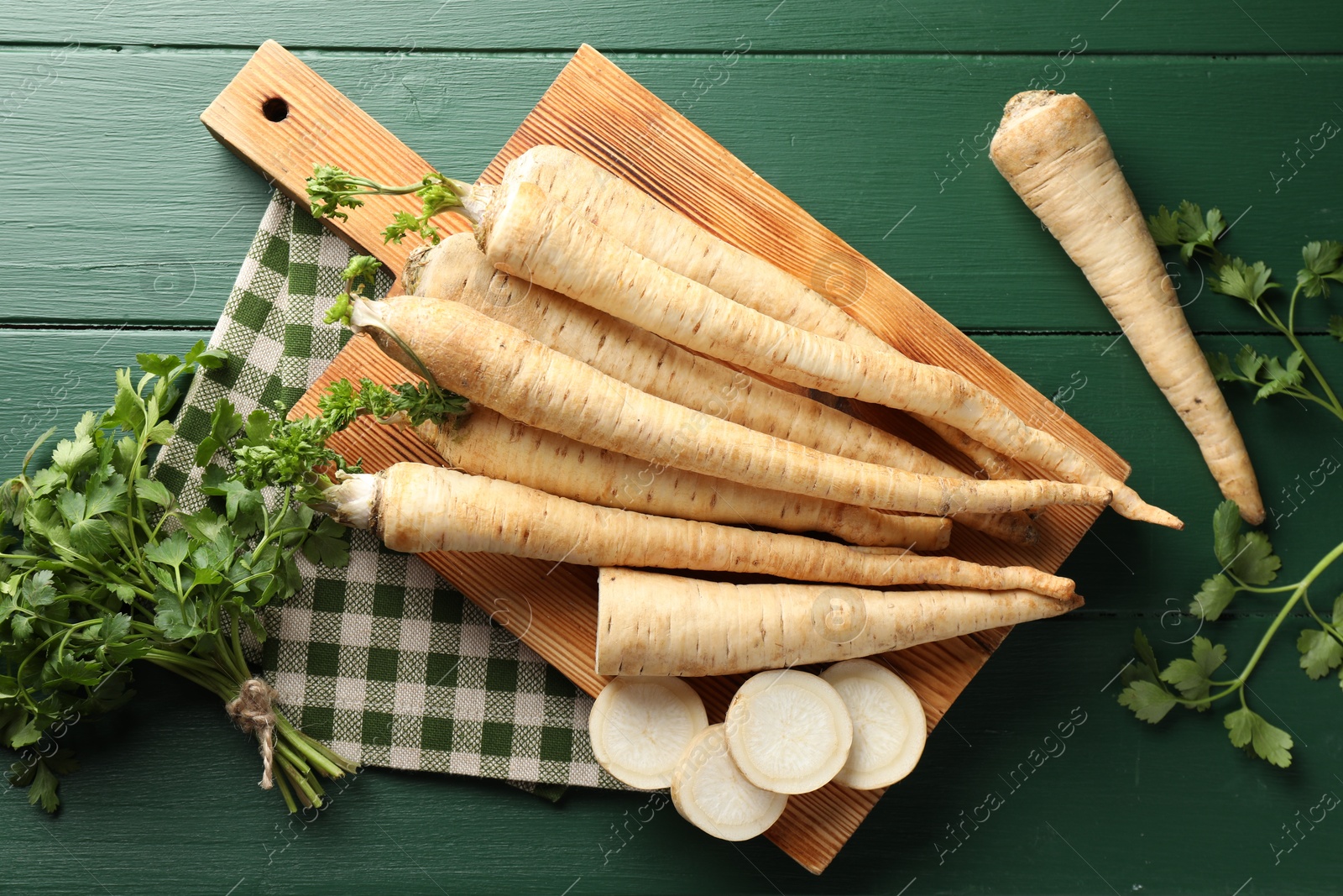 Photo of Parsley roots and leaves on green wooden table, flat lay