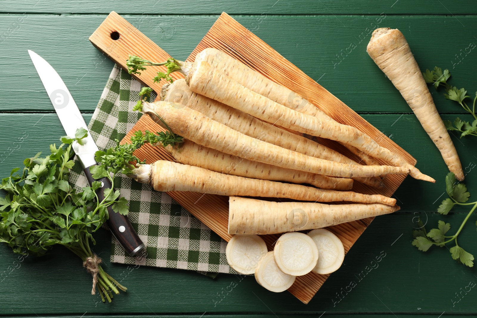 Photo of Parsley roots and leaves with knife on green wooden table, flat lay