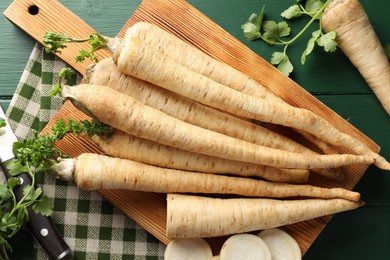 Photo of Parsley roots with leaves on green wooden table, flat lay