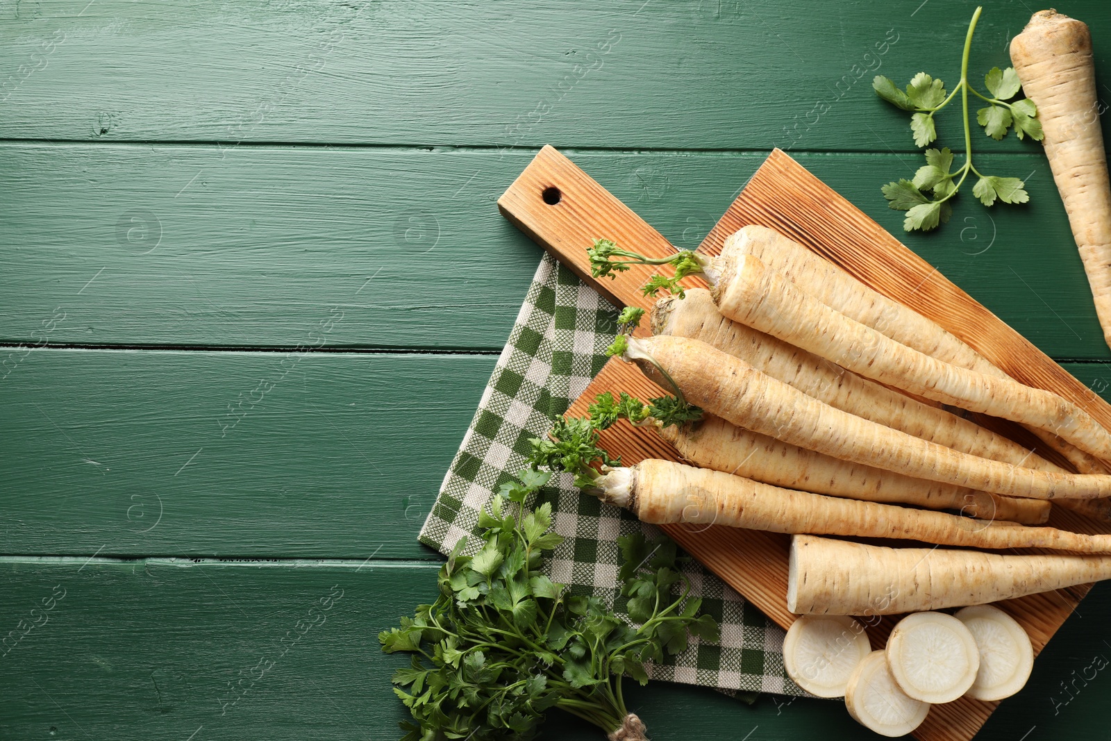 Photo of Parsley roots and leaves on green wooden table, flat lay. Space for text