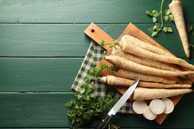 Photo of Parsley roots and leaves with knife on green wooden table, flat lay. Space for text