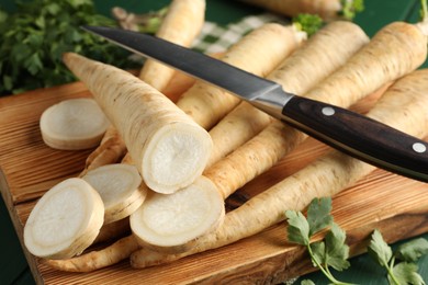 Photo of Parsley roots and leaves with knife on green table, closeup