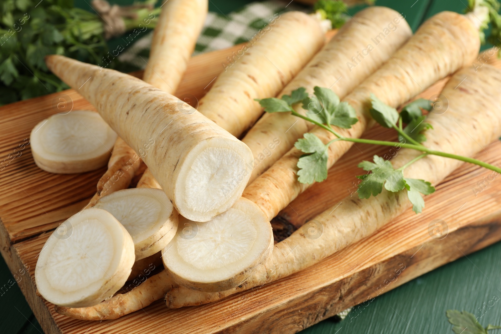 Photo of Parsley roots and leaves on green wooden table, closeup