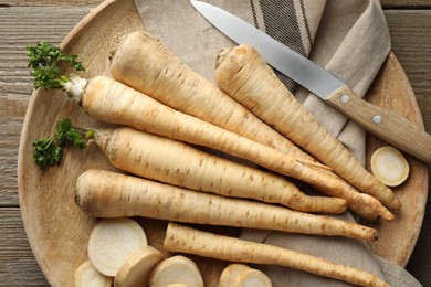 Photo of Parsley roots and knife on wooden table, top view