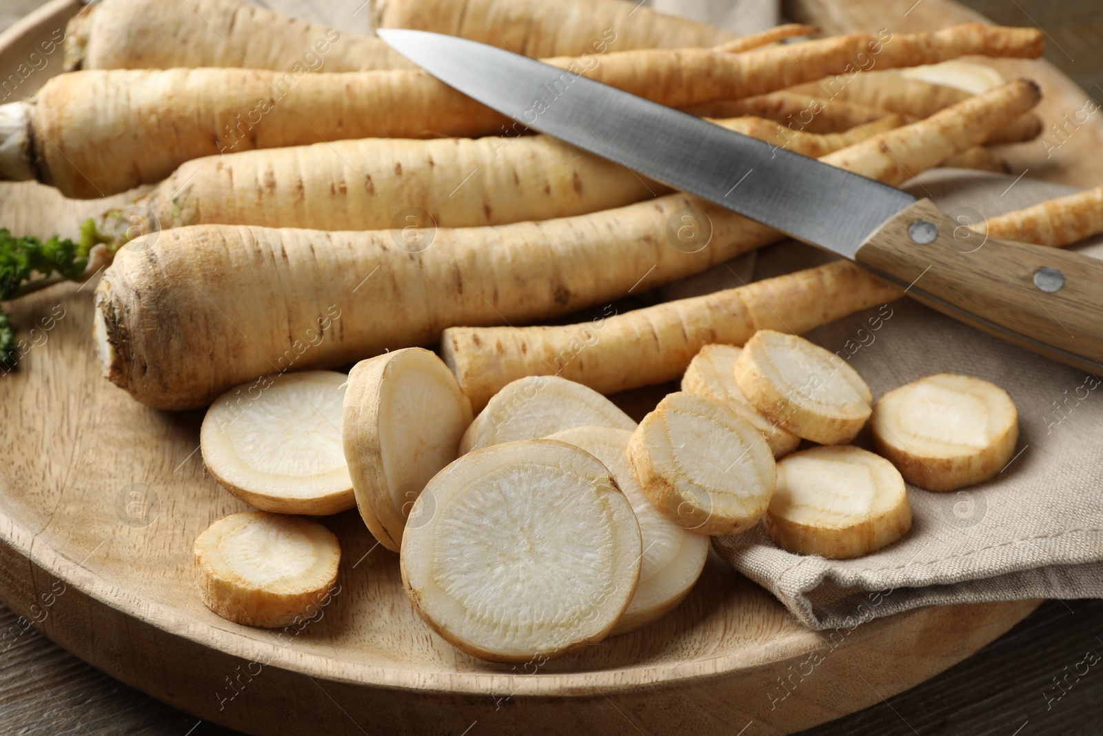 Photo of Parsley roots and knife on wooden table, closeup