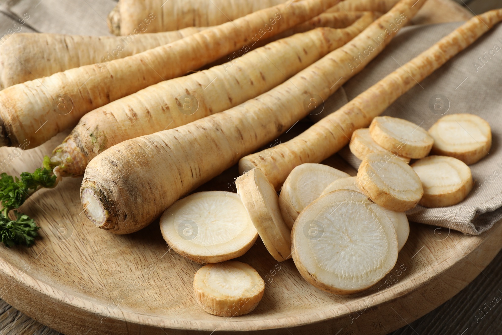 Photo of Raw parsley roots on wooden table, closeup