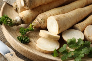 Photo of Parsley roots and leaves with knife on wooden table, closeup