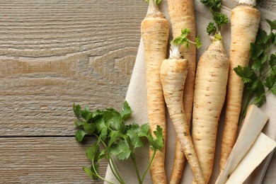 Photo of Raw parsley roots with leaves on wooden table, top view. Space for text