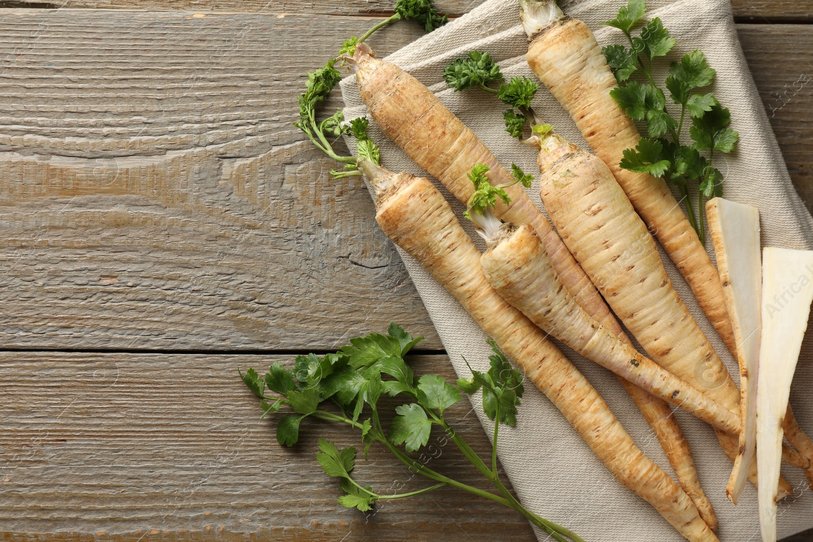 Photo of Raw parsley roots with leaves on wooden table, top view. Space for text