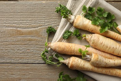 Photo of Raw parsley roots with leaves on wooden table, top view. Space for text