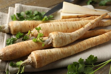 Photo of Raw parsley roots with leaves on table, closeup