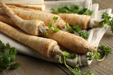 Photo of Raw parsley roots with leaves on wooden table, closeup