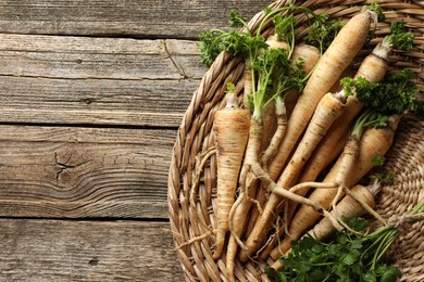 Photo of Raw parsley roots with leaves on wooden table, top view. Space for text