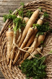 Photo of Raw parsley roots with leaves on wooden table, top view