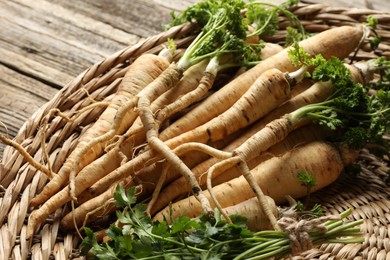 Photo of Raw parsley roots with leaves on wooden table, closeup