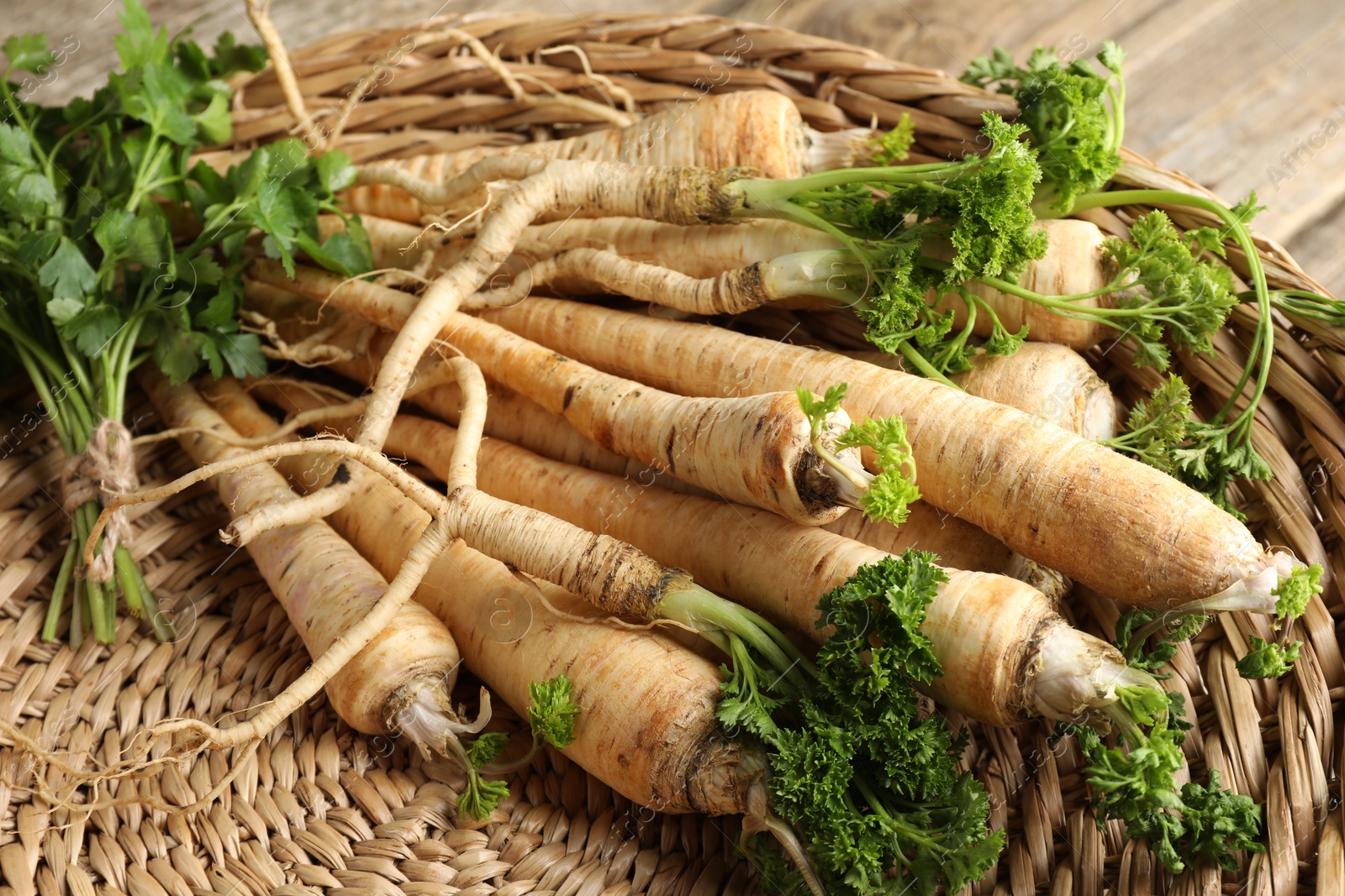 Photo of Raw parsley roots with leaves on table, closeup