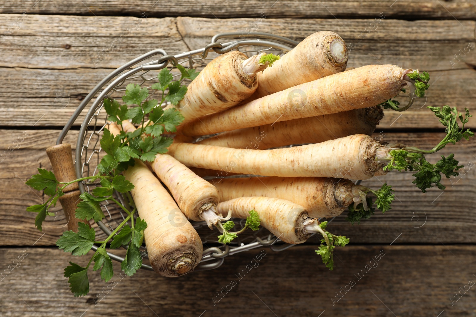 Photo of Raw parsley roots with leaves on wooden table, top view