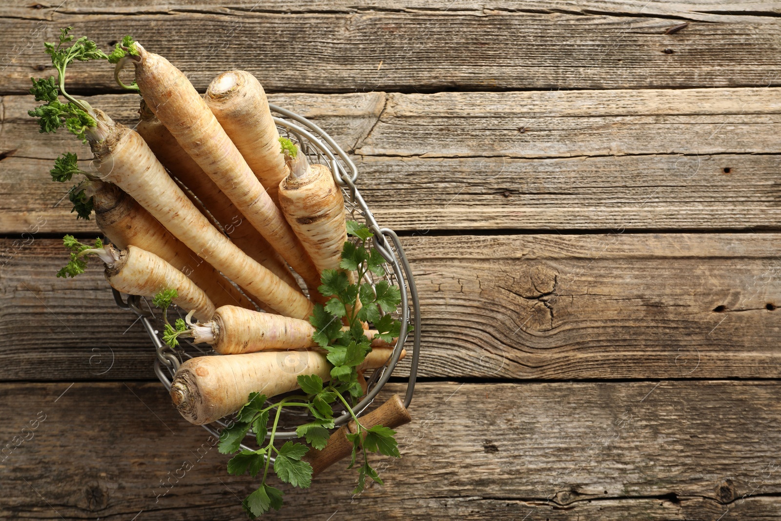 Photo of Raw parsley roots with leaves on wooden table, top view. Space for text