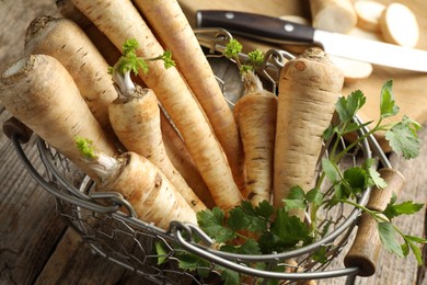 Photo of Raw parsley roots with leaves on wooden table, closeup