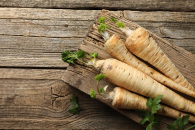 Photo of Raw parsley roots with leaves on wooden table, top view. Space for text